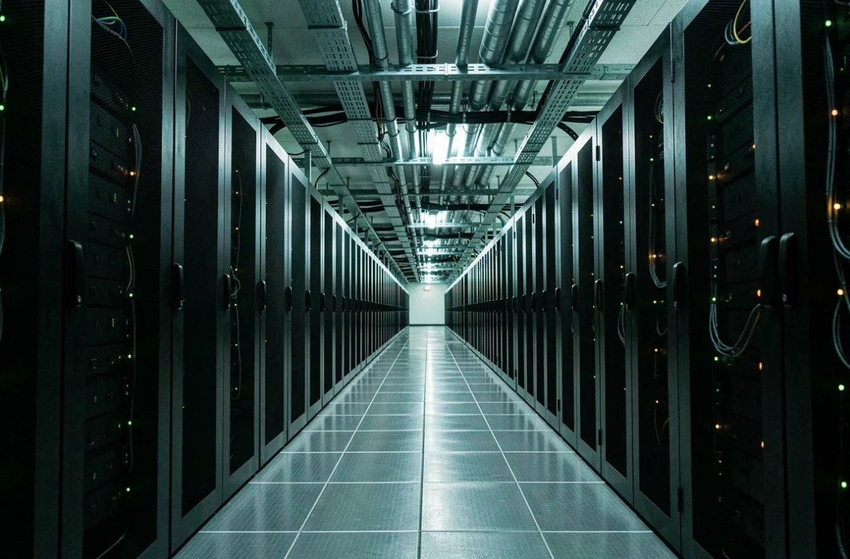 Couloir d'un centre de données avec des rangées de serveurs informatiques, illustrant l'empreinte carbone et la consommation énergétique du numérique