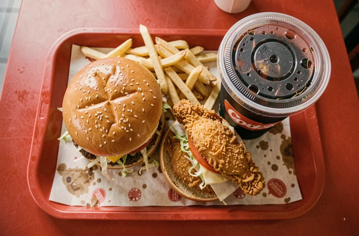 Plateau de fast-food avec burger, frites et cola vus de dessus, symbolisant les aliments à éviter pour la santé du cerveau